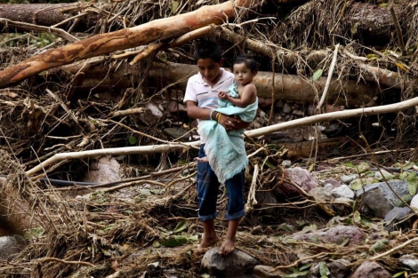 Un nio cruza una zona afectada con su hermana en brazos. | Reuters