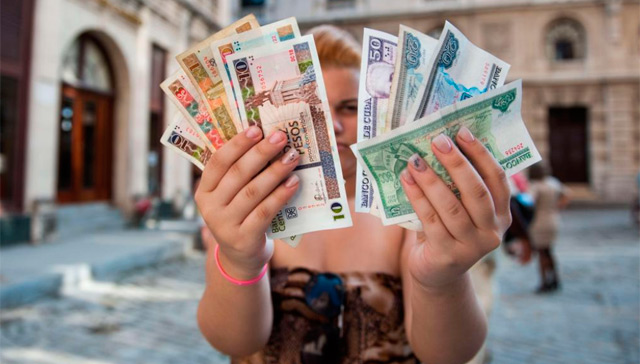 Una mujer muestra pesos cubanos y pesos convertibles. | Afp