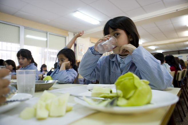 Varias nias comiendo dentro de un comedor escolar.