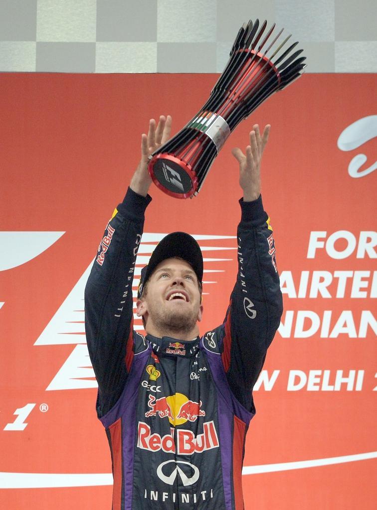 Vettel lanza al aire el trofeo conseguido en la India.