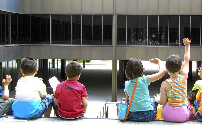 Varios niños sentados de espaldas en el patio de un colegio