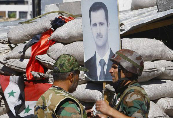 Soldados leales a Bashar Asad, ante una imagen suya en Damasco.