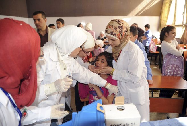 Personal sanitario vacuna a las niñas en un colegio de Damasco.