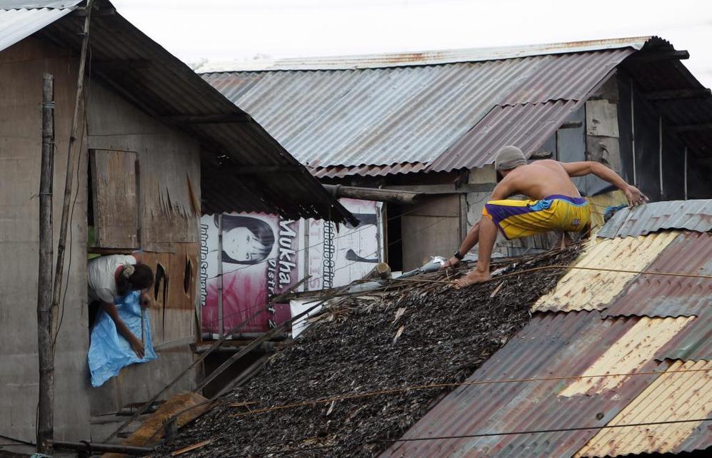 Residentes filipinos refuerzan sus viviendas ante la llegada del tifón 'Haiyan'.