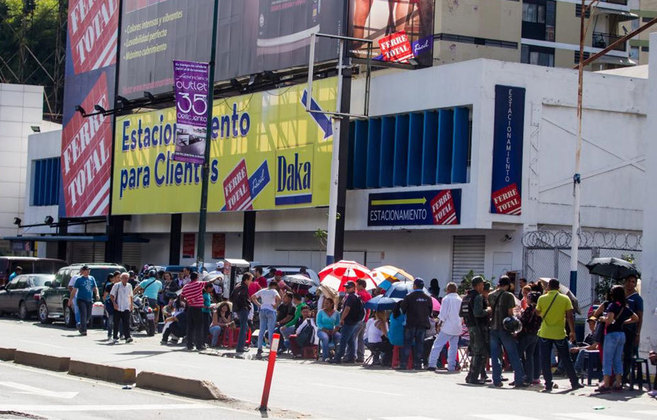 Un grupo de personas espera para poder realizar compras en Caracas.