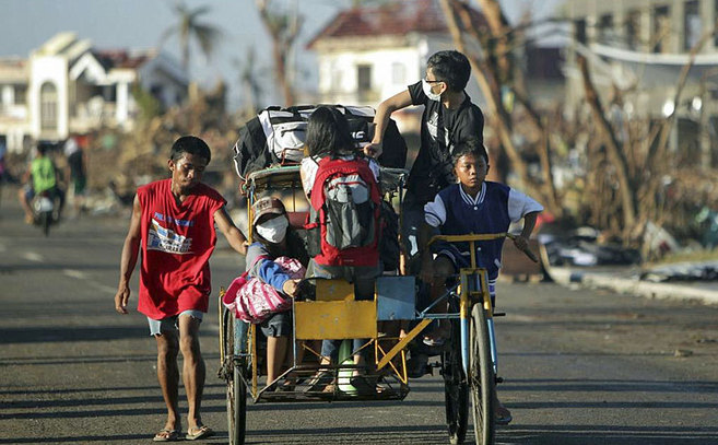 Supervivientes del tifón montan en bicicleta a la salida de su casa...