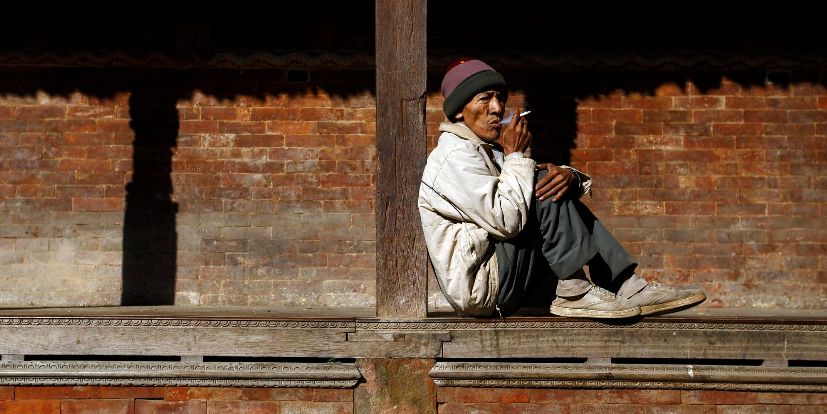 Un hombre fuma un cigarro a las afueras de un templo en Katmand,...