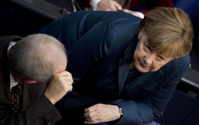 Merkel habla con su ministro de Finanzas en el Parlamento alemán, en...