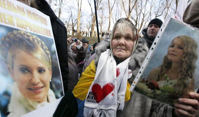 Una anciana sujeta la foto de la encarcelada primer ministra, Yulia...