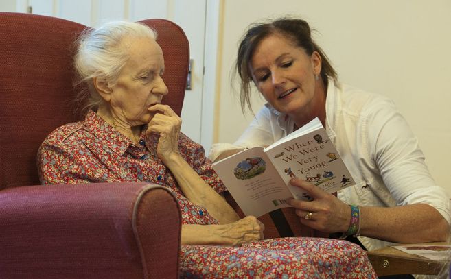 Una voluntaria de 'Kissing it better' lee a una anciana en...