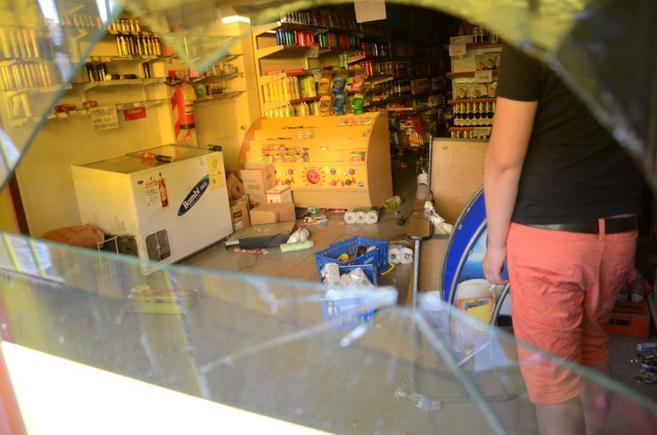 Un trabajador contempla los destrozos de su tienda durante los saqueos...