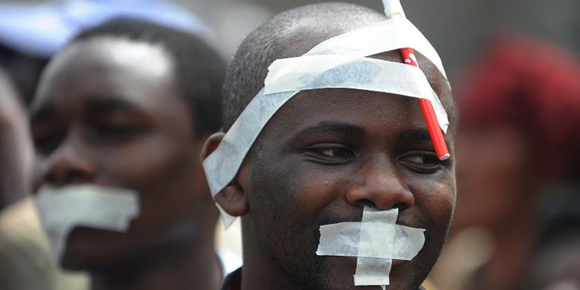 Los hombres con la cinta en la boca participan en una marcha convocada...