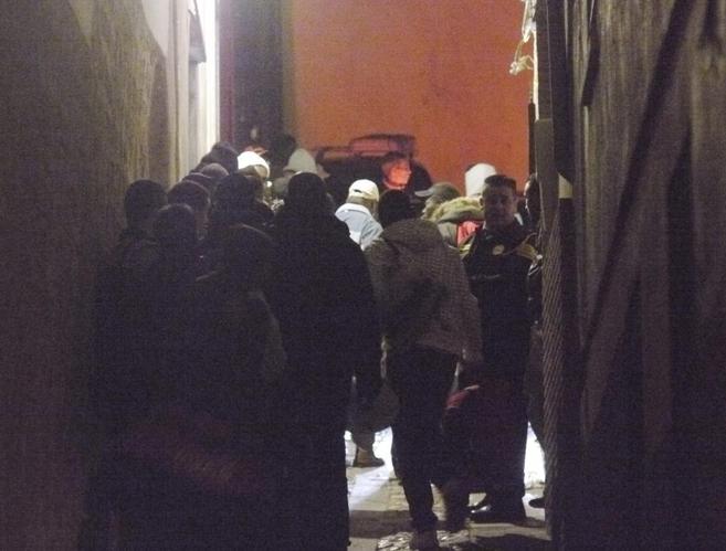 Grupos de inmigrantes hacen cola para entrar en un albergue de...