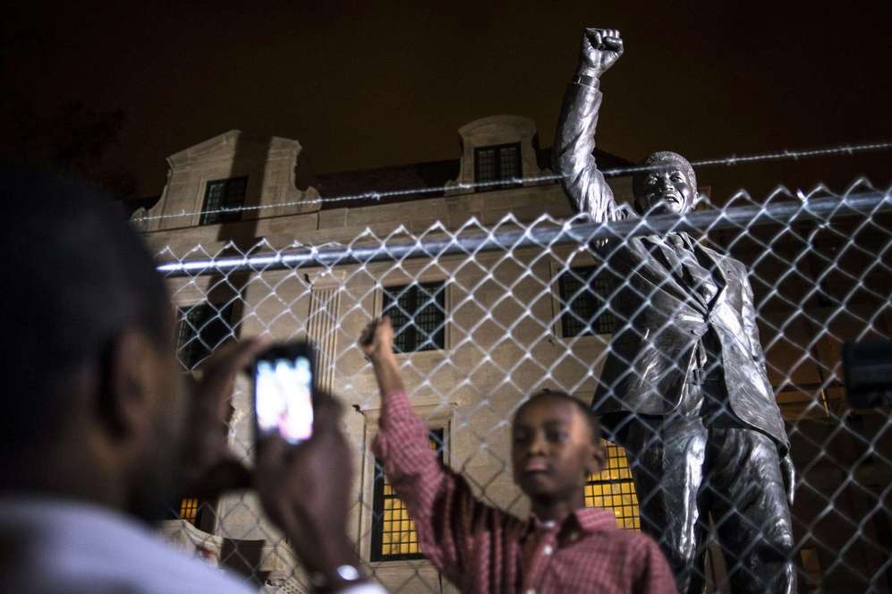 Un nio se fotografa delante de una estatua de Nelson Mandela en...