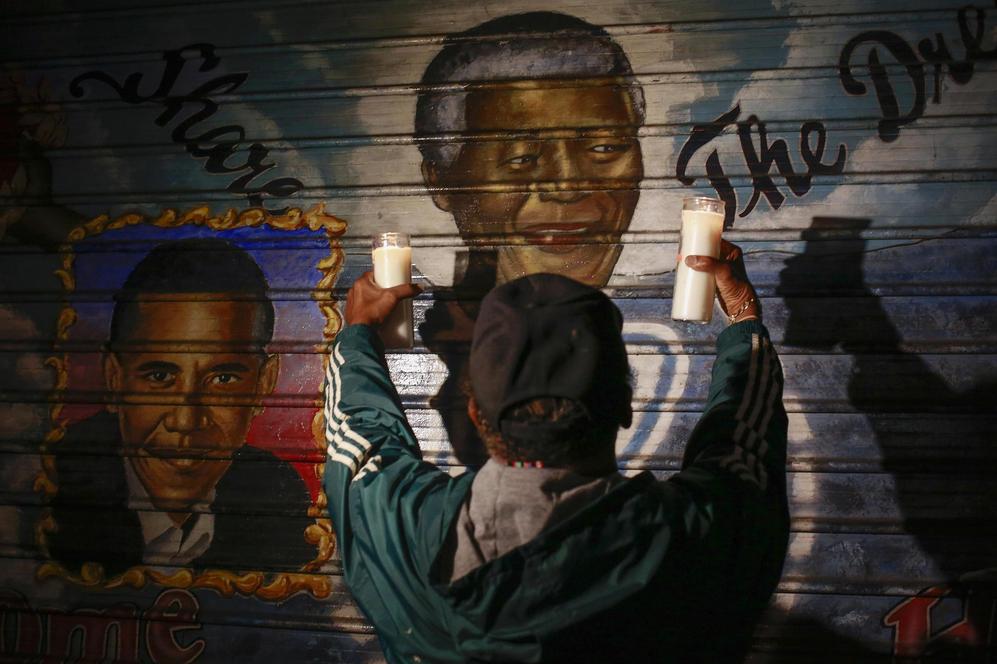 Un nio con dos velas delante de un mural de Mandela en Nueva York.