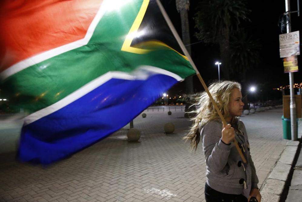 Una nia sostiene la bandera de Sudfrica en seal de duelo.
