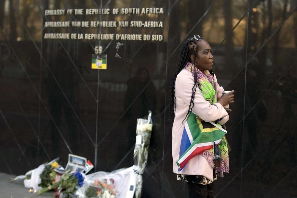 Una mujer coloca flores en memoria a Mandela frente a la embajada de...