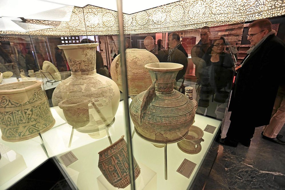 Un grupo de visitantes observa las vasijas expuestas en la muestra...