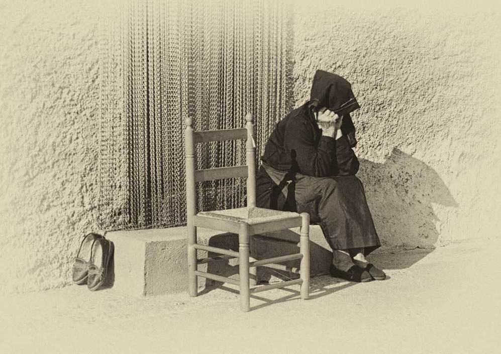 Una mujer sentada a la puerta de su casa, esperando la tertulia del atardecer en Montehermoso, Cceres.