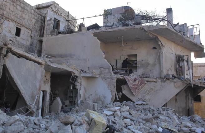 Una mujer inspecciona su devastada casa en Alepo.