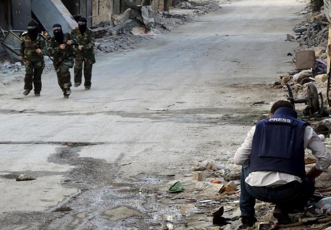 Milicianas yihadistas pasan junto a un periodista, en Alepo.