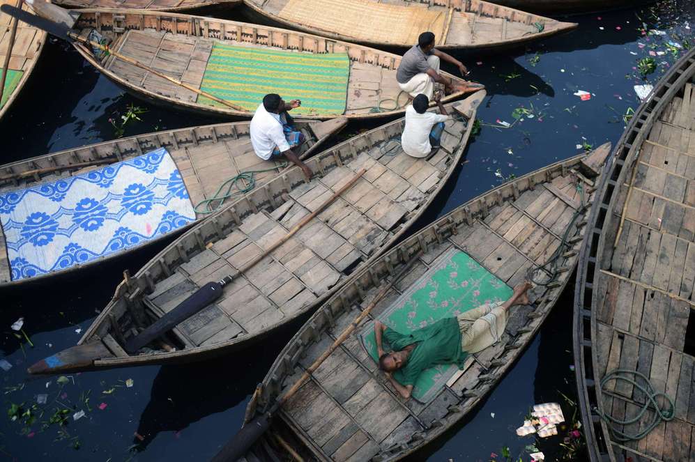 Barqueros bangladeses descansando en sus barcas durante un bloqueo...