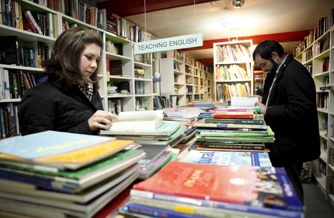 Dos jóvenes consultan libros para aprender inglés.