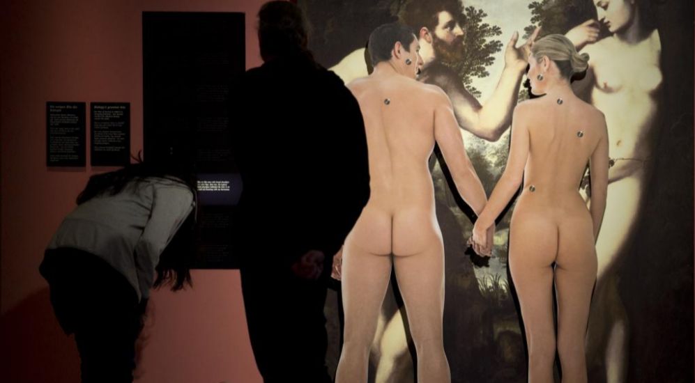 Una pareja desnuda de espaldas en una exposición