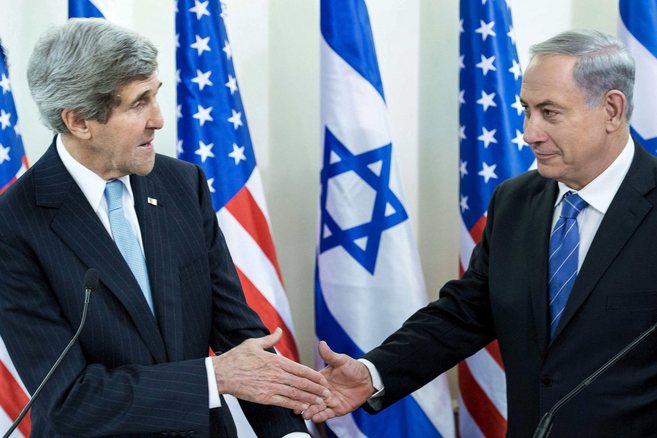 John Kerry (izqda.) y Benjamin Netanyahu se dan la mano antes de su...