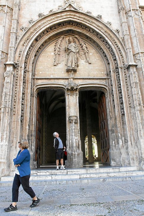 Dos turistas pasean junto al portal principal de La Lonja, edificio...