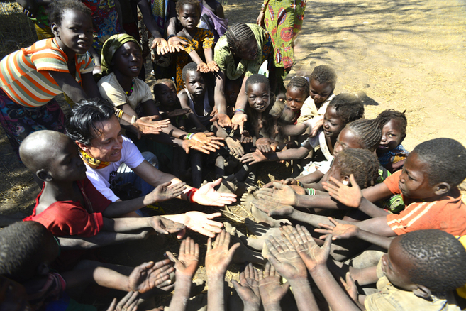 Un grupo de niños africanos rodea a un doctor occidental