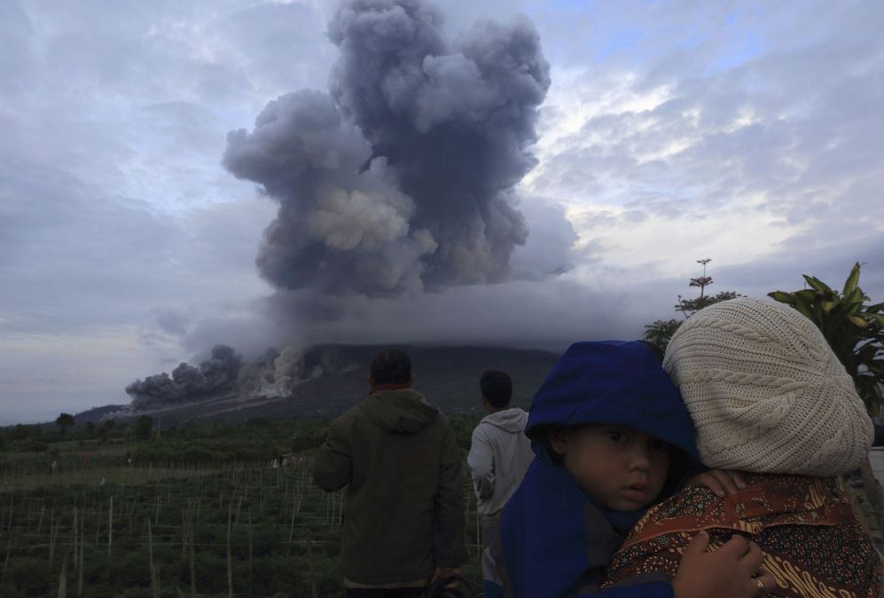 Una madre sostiene a su hijo en brazos mientras ven la erupcin del...