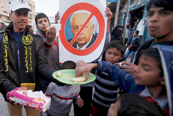 Unos palestinos celebran con dulces la noticia del fallecimiento del...
