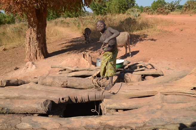 Un niño africano recoge agua de un pozo