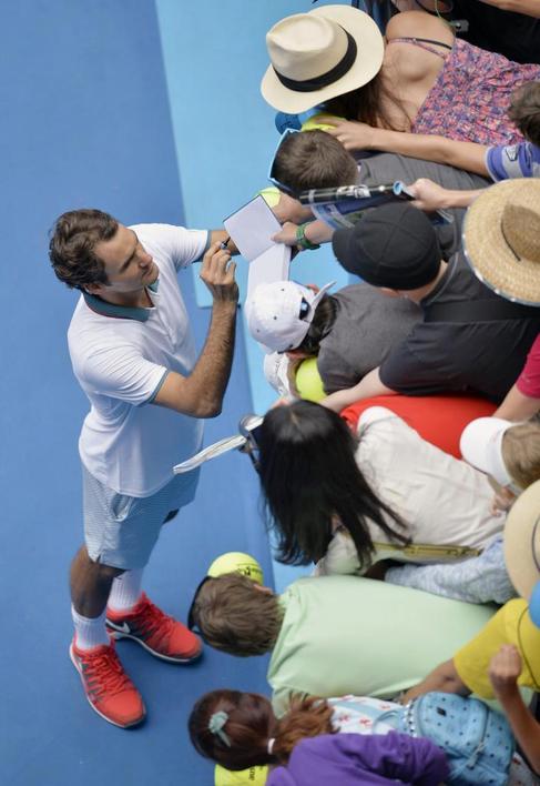 Roger Federer firma autgrafos tras su victoria.
