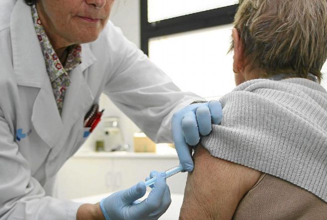 Una profesional sanitaria dispensa una vacuna contra la gripe a una...