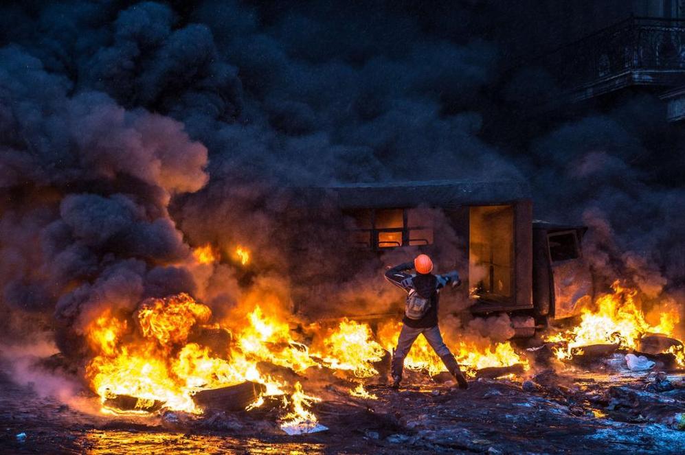 Un manifestante lanza  objetos a un camin ardiendo. Durante las...