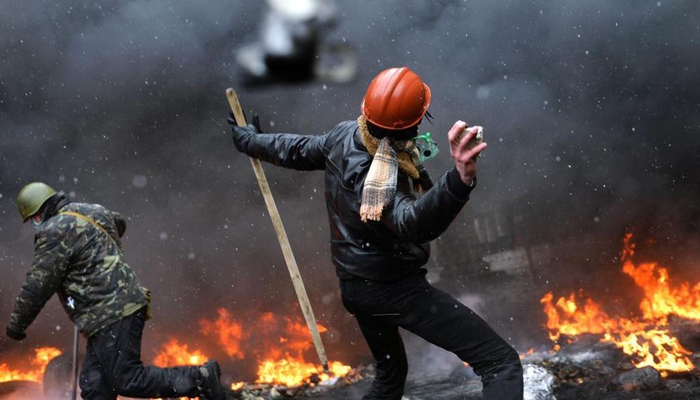Un manifestante, protegido con un casco y agarrando una estaca, lanza...