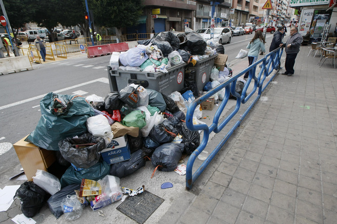 Contenedores rebosantes y basura acumulada en la calle como...