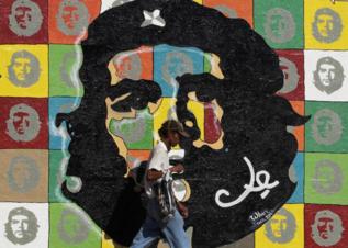 Un hombre camina por delante de un mural del Che.