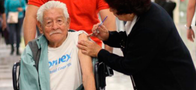 Un anciano recibe la vacuna contra la gripe AH1N1 en el aeropuerto...