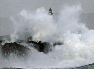 Una ola rompe sobre la isla de Mouro en Santander.