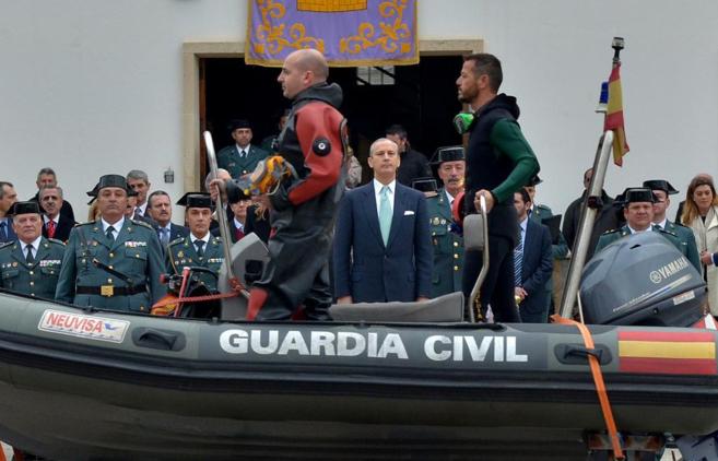 En primer plano, un barco de la Guardia Civil con dos agentes en traje...