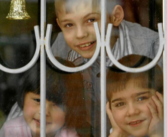 Nios rusos se asoman por la ventana de un orfanato en una ciudad al...