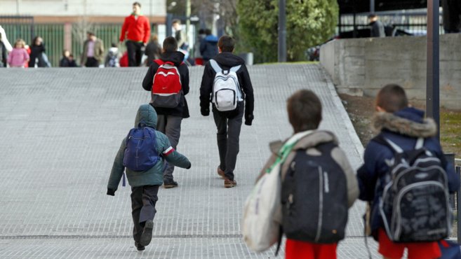 Niños cargados con sus mochilas camino del colegio.
