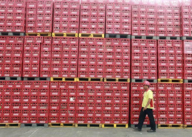Un trabajador pasando junto a decenas de cajas de Coca- Cola.