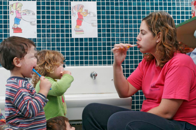 Dos niños aprenden a lavarse los dientes en la guardería.