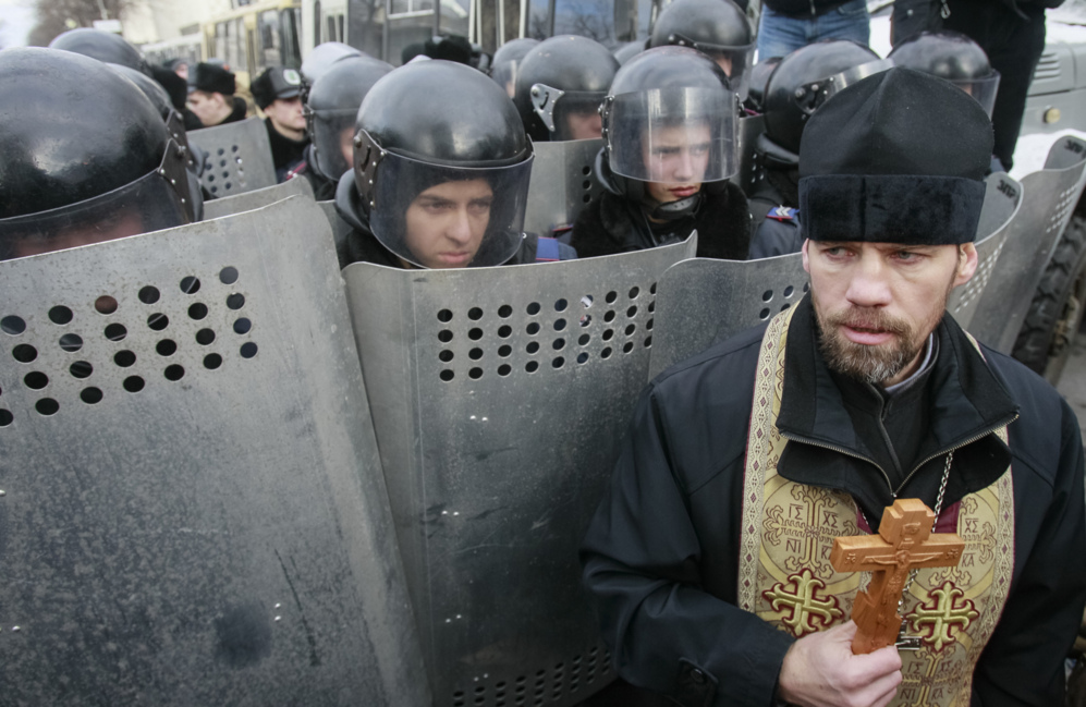 14 de Enero del 2014. Un sacerdote intentado bloquear a la polica.