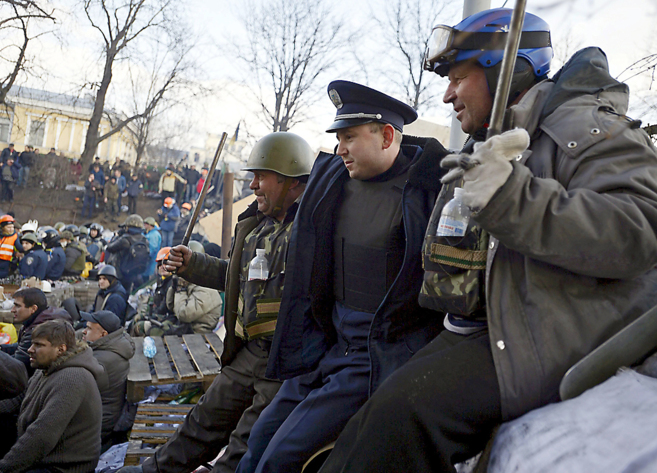 Un polica de la ciudad de Lviv posa junto a dos manifestantes en el...