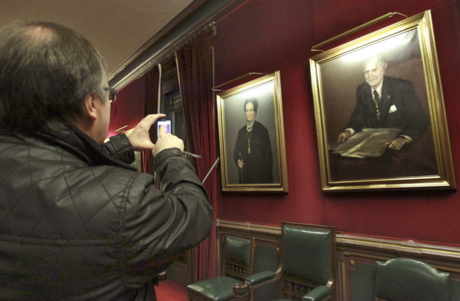 Un hombre fotografa los cuadros de los alcaldes, en la sala en la...